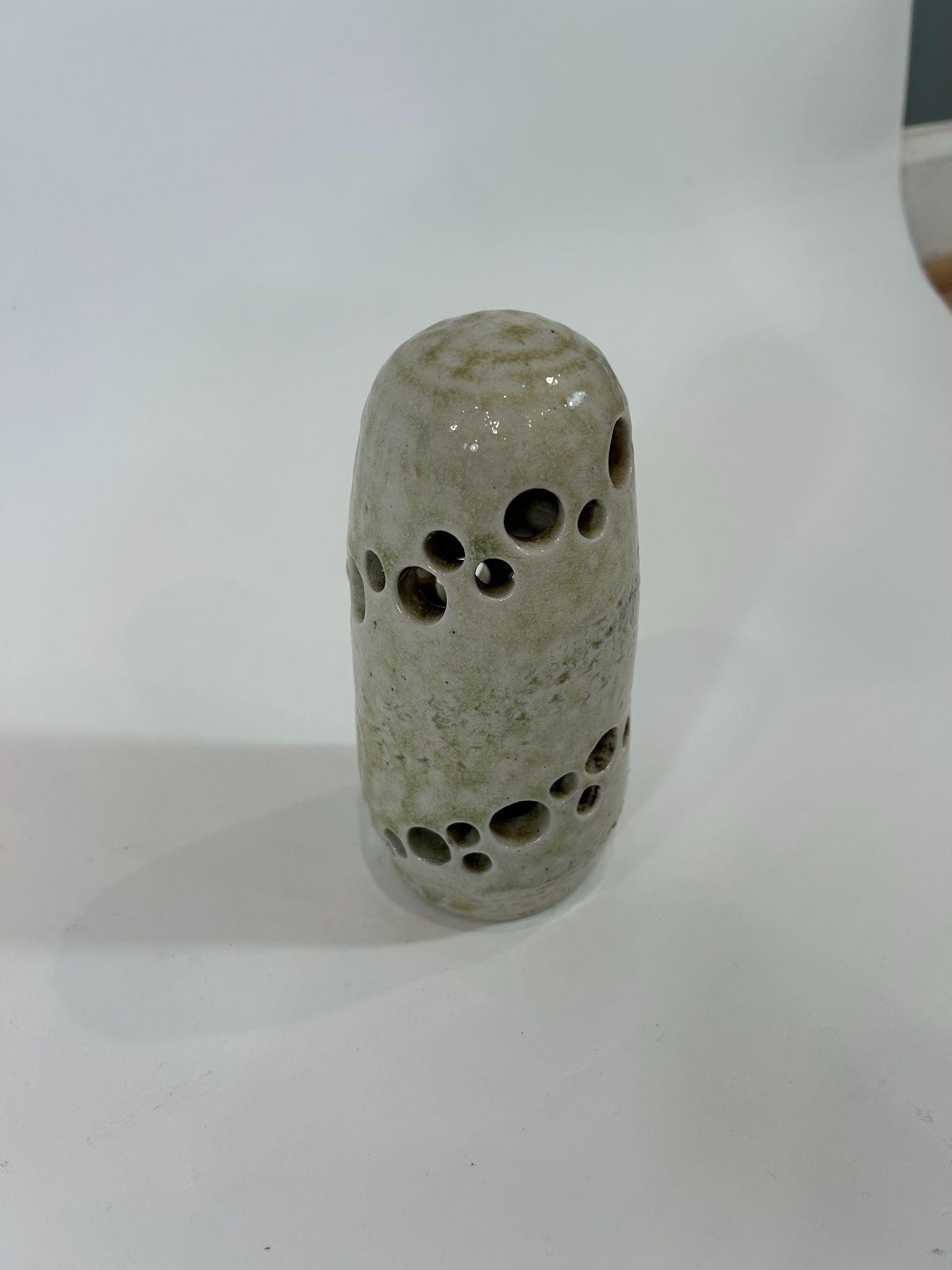 A wood-fired vessel pierced with holes and glazed by ash